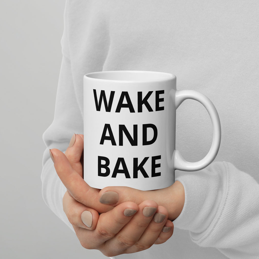 White glossy mug held in hands with “WAKE AND BAKE” text